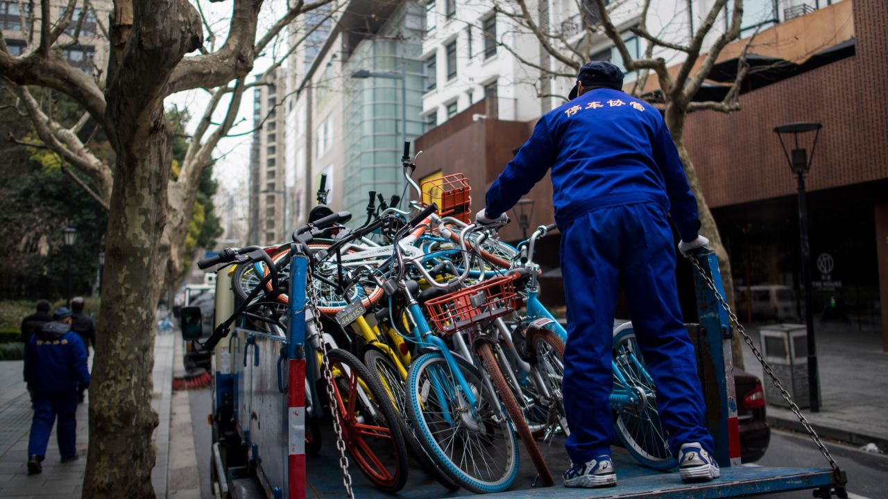 This picture taken on February 20, 2017 shows an employee of a parking firm putting bicycles from the bike-sharing schemes into  a truck in Shanghai.  