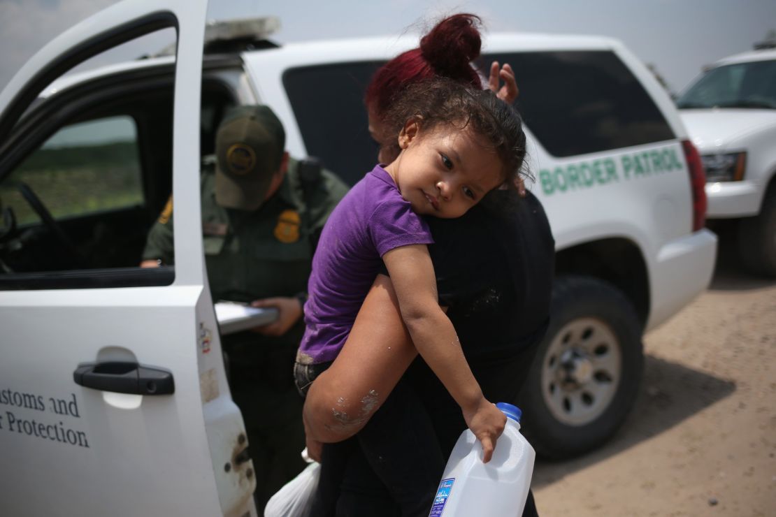 A mother and her 3-year-old child from El Salvador await transport to an immigrant processing center after they crossed the Rio Grande into the United States on July 24, 2014.