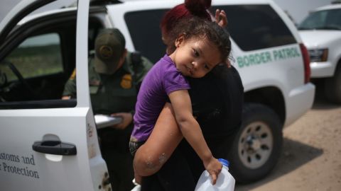 A mother and her 3-year-old child from El Salvador await transport to an immigrant processing center after they crossed the Rio Grande into the US on July 24, 2014.
