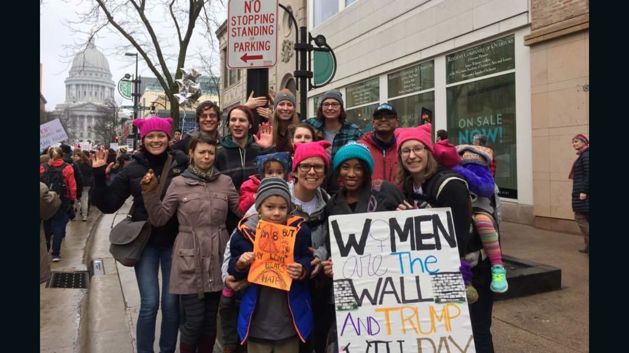 Charisse Daniels, in the teal hat, holds a sign saying, "Women are the wall and Trump will pay."