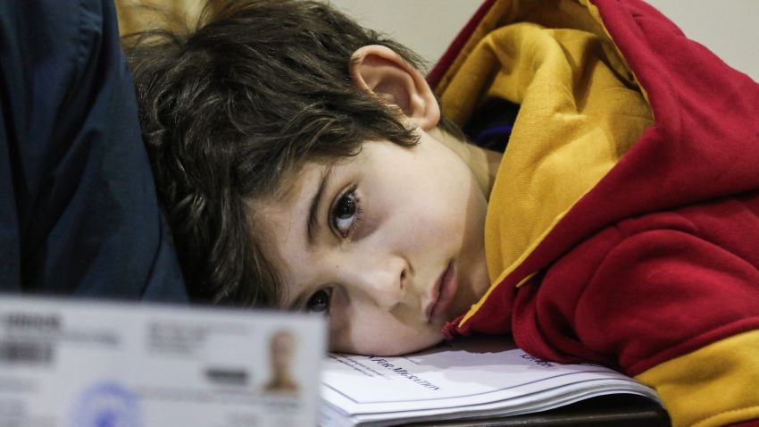Ward Faraj al-Jamous, a child Syrian refugee, rests his head on a stack of documents as his father gives an interview, after his family was prevented from travel to the United States when President Donald Trump's executive order blocking entry to citizens from seven Muslim-majority countries, including Syria, was enacted without warning, in the Jordanian capital Amman on February 1, 2017.
After spending over a year amid interviews, health and security checks, the Jamous family of seven was contacted by a representative from the International Organisation of Migration (IOM) who told him that the family's immigration and resettlement plans were suspended indefinitely. / AFP / Khalil MAZRAAWI        (Photo credit should read KHALIL MAZRAAWI/AFP/Getty Images)