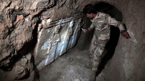 An Iraqi troop member examines ancient artifacts found in an underground ISIS tunnel in eastern Mosul. 