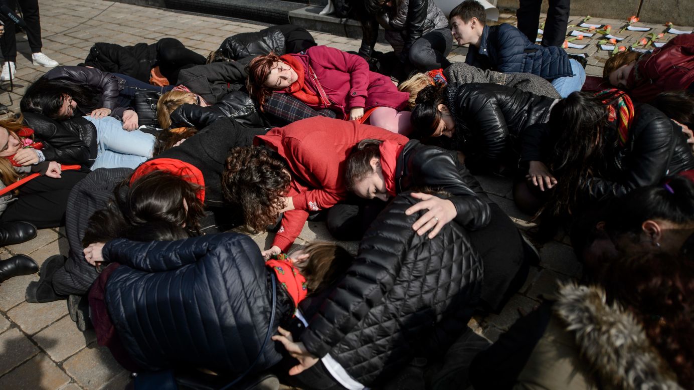 People in Bucharest, Romania, lie on the ground during a performance to raise awareness about women killed by their partners.