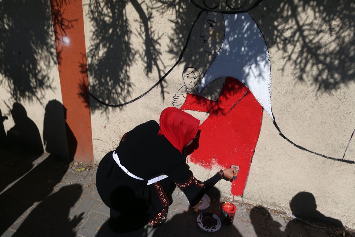 A Palestinian artist applies the final touches to a street mural in Gaza City.