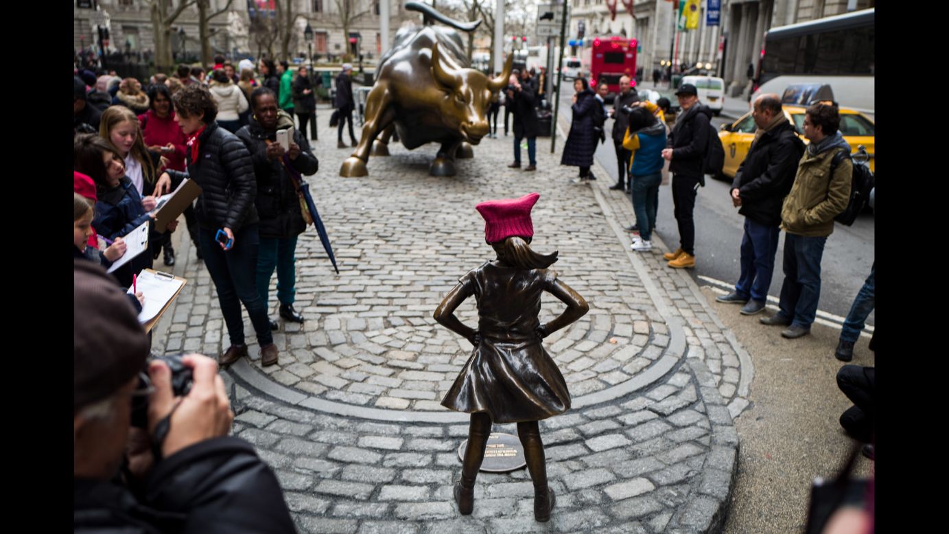 A crowd gathers in Lower Manhattan to see the statue of the defiant girl in front of the charging bull on March 8. The statue is expected to remain in place for at least a week, but State Street Global Advisors and others involved in the project are seeking an extension of a month.
