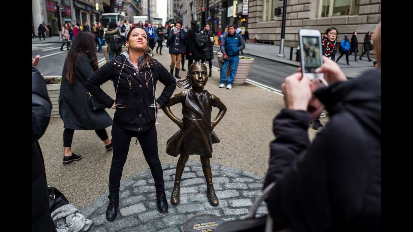 A woman mimics the defiant stance of the "Fearless Girl."