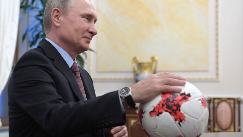 Russian President Vladimir Putin places his hand on an official match ball for the 2017 FIFA Confederations Cup, named "Krasava"