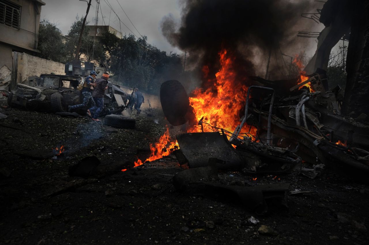 Burning flames engulf a car after a bomb, planted by ISIS, exploded at provisional base of the Iraqi Federal Police in Mosul. Wounded soldiers run to safety right before a second car bomb exploded in the same area.