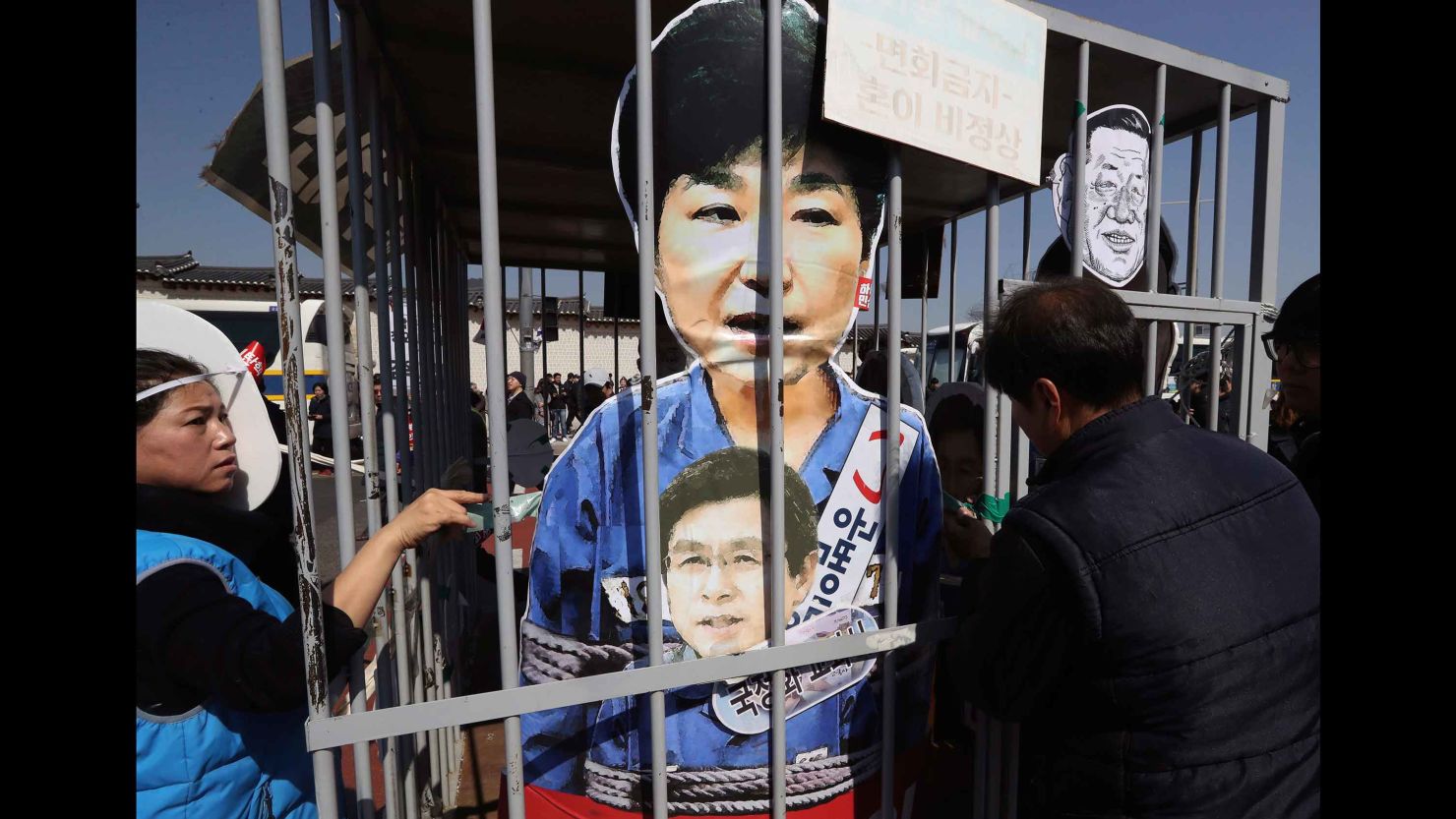 Protesters in Seoul, South Korea, look at cut-outs of impeached President Park Geun-hye, top, and acting leader and Prime Minister Hwang Kyo-ahn, bottom, in a mock jail as they march Friday toward the presidential house after the Constitutional Court voted to oust Park.