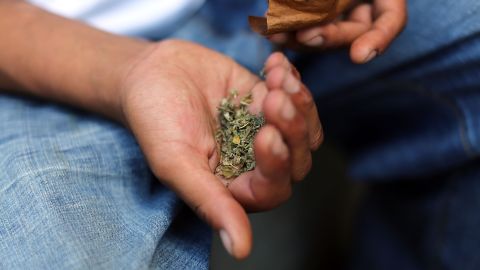 A man prepares to smoke K2 or "Spice", a synthetic marijuana drug, along a street in East Harlem on August 5, 2015 in New York City. 