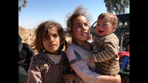 Two girls hold their little brother as they wait for Iraqi security forces to transfer them to a nearby refugee camp.
