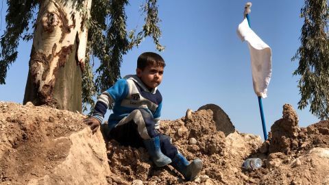 A boy climbs over a dirt mound near the Mosul airfield. White flags like the one next to him were carried by many families and civilians who fled western Mosul as fighting between Iraqi forces and ISIS raged.
