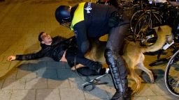 A Dutch riot police officer tries to get his dog to let go of a man after riots broke out during a demonstration at the Turkish consulate in Rotterdam, Netherlands, on Sunday, March 12.