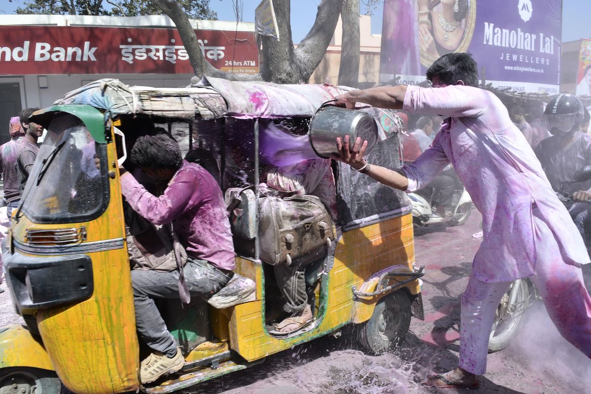 A man celebrating Holi dumps a bucket of colored water onto people in Mathura, India, on Monday, March 13.