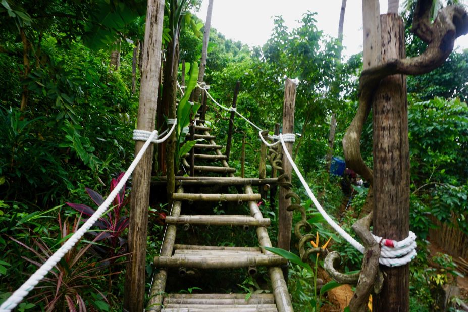 <strong>Forest trek:</strong> Follow the signs on a trek through the forest. Finally, a stairwell leads travelers up a lush mountainside where contemporary tents are visible between the tree branches.