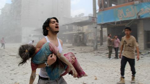 A man carries a young girl who was injured on June 3, 2014 in Kallaseh district in the northern city of Aleppo.