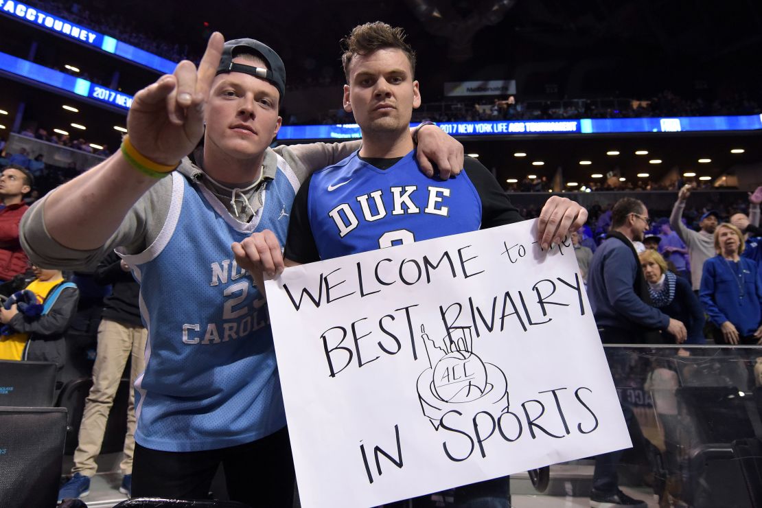 A fan of the North Carolina Tar Heels and the Duke Blue Devils pose for a photo while holding a sign referring to the Duke/UNC rivalry during the ACC Basketball Tournament at Barclays Center on Friday.
