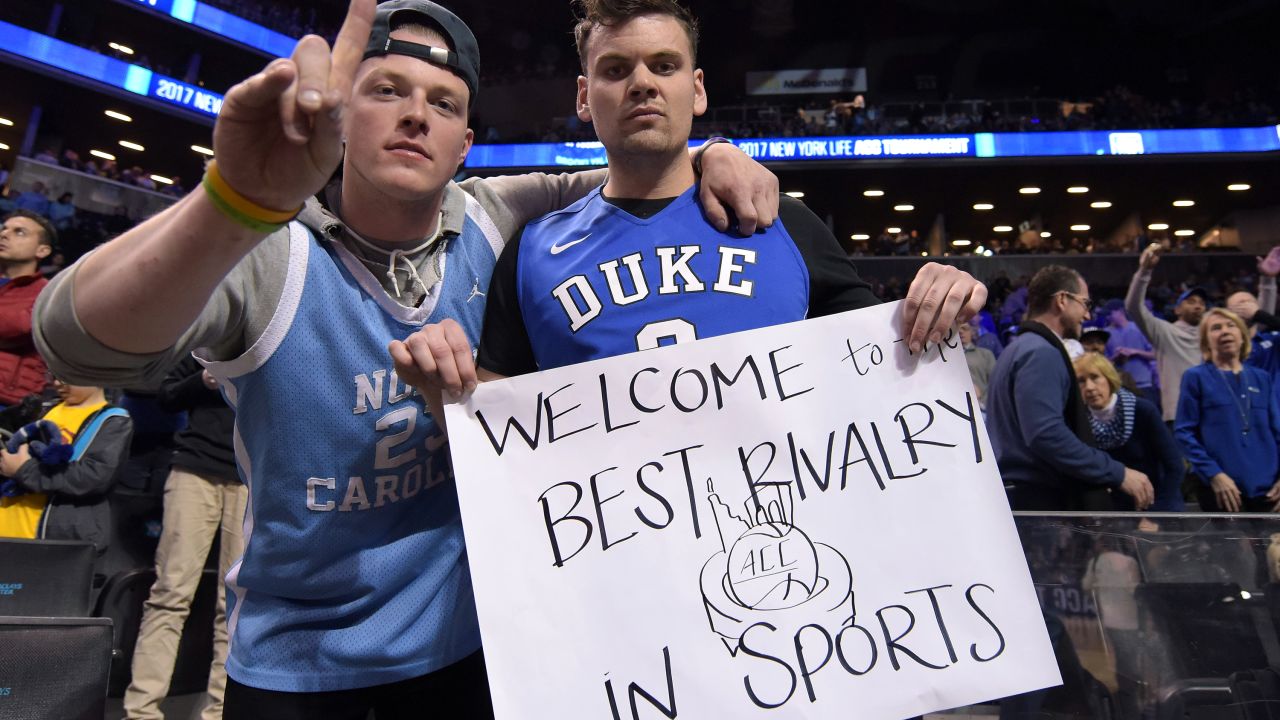 A fan of the North Carolina Tar Heels and the Duke Blue Devils pose for a photo while holding a sign referring to the Duke/UNC rivalry during the ACC Basketball Tournament at Barclays Center on Friday.
