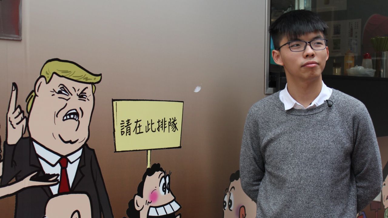 Joshua Wong poses with a mural of US President Donald Trump in Hong Kong's Sheung Wan district.