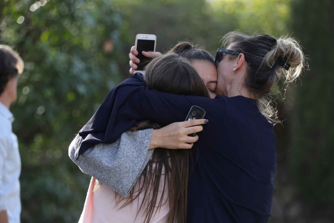 People react near the high school following the shooting.