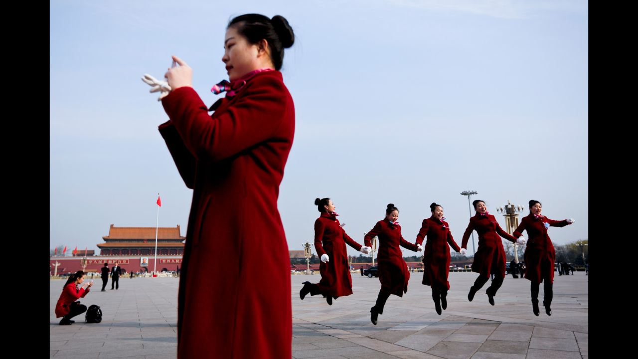 Hospitality staff members jump for a photo at Beijing's Tiananmen Square on Wednesday, March 15. Beijing was hosting the closing session of the National People's Congress.