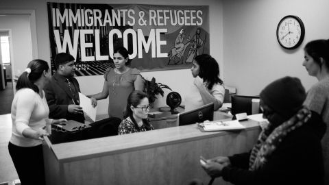 Catholic Charities staff speak with immigrants waiting to talk to lawyers.