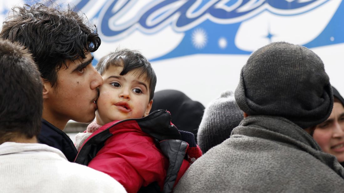 A man kisses his child as they prepare to get on a bus.