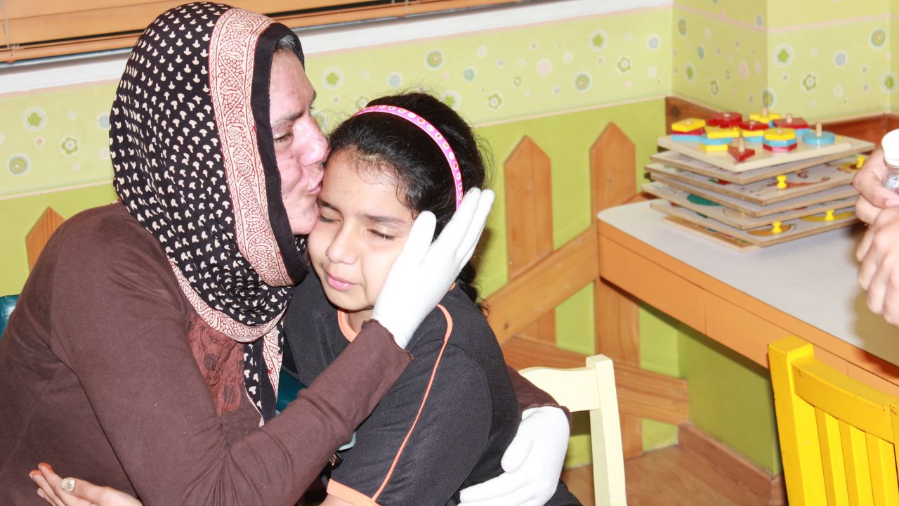 Chaphekar tenderly kisses her daughter on the forehead as she continues to recover from her injuries. The doting mother is seen here wearing protective gloves.