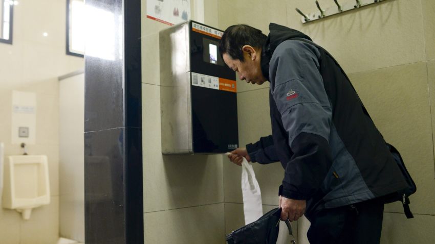 A man uses an automatic toilet paper dispenser that uses facial recognition technology at a public toilet at the Temple of Heaven in Beijing on March 21, 2017. 
A years-long crime spree by Chinese toilet paper thieves may have reached the end of its roll after park officials in southern Beijing installed facial recognition technology to flush out bathroom bandits. / AFP PHOTO / WANG Zhao        (Photo credit should read WANG ZHAO/AFP/Getty Images)