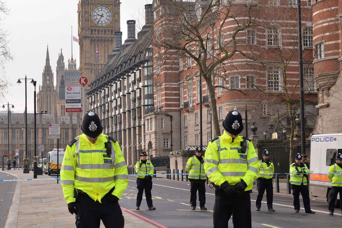 British police officers patrolling near Houses of Parliament bow their heads.