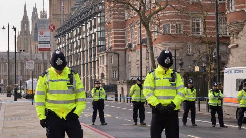 British police officers patrolling near Houses of Parliament bow their heads.