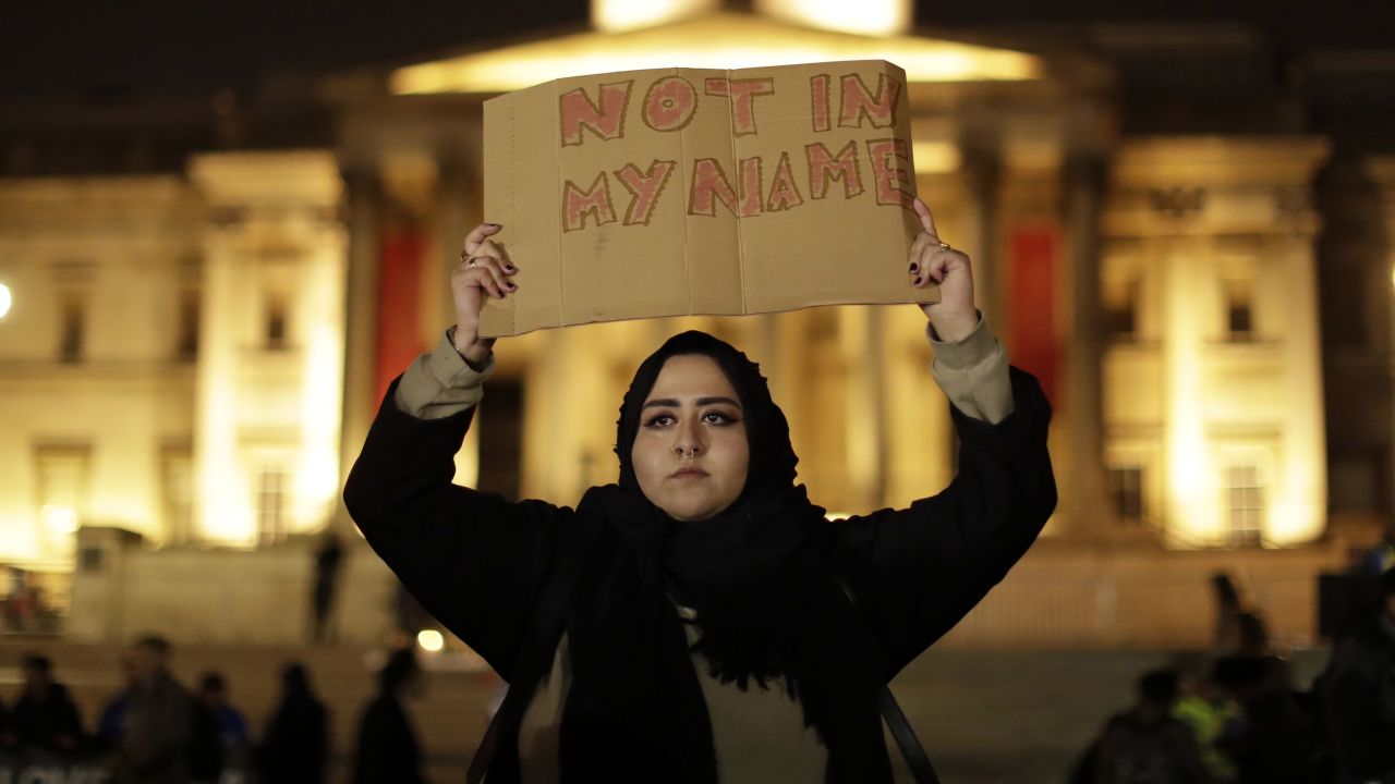 A woman wearing traditional Muslim dress holds up a sign at the vigil.