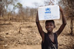 A South Sudanese refugee carries a relief box in Uganda.