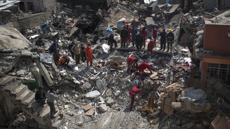 Civil protection rescue teams comb through the debris of a destroyed house to recover the bodies of people killed during fights between Iraq security forces and the Islamic State on the western side of Mosul.