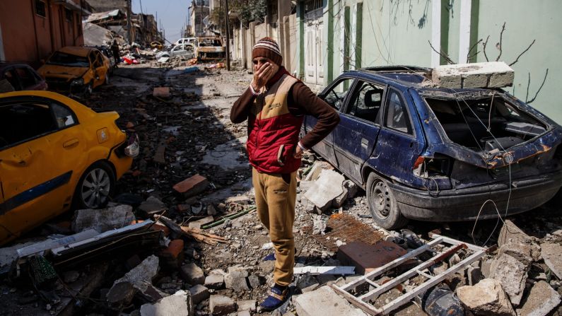 A man covers his face from the smell of corpses in the al Jadidah neighborhood of Mosul on March 24, 2017. 