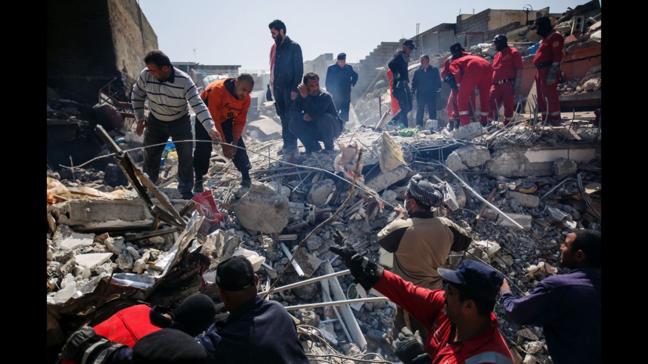 Residents help Iraqi civil defense force members recover corpses trapped in the rubble of a home destroyed by reported coalition airstrikes in the al Jadidah neighborhood of Mosul on March 24, 2017.