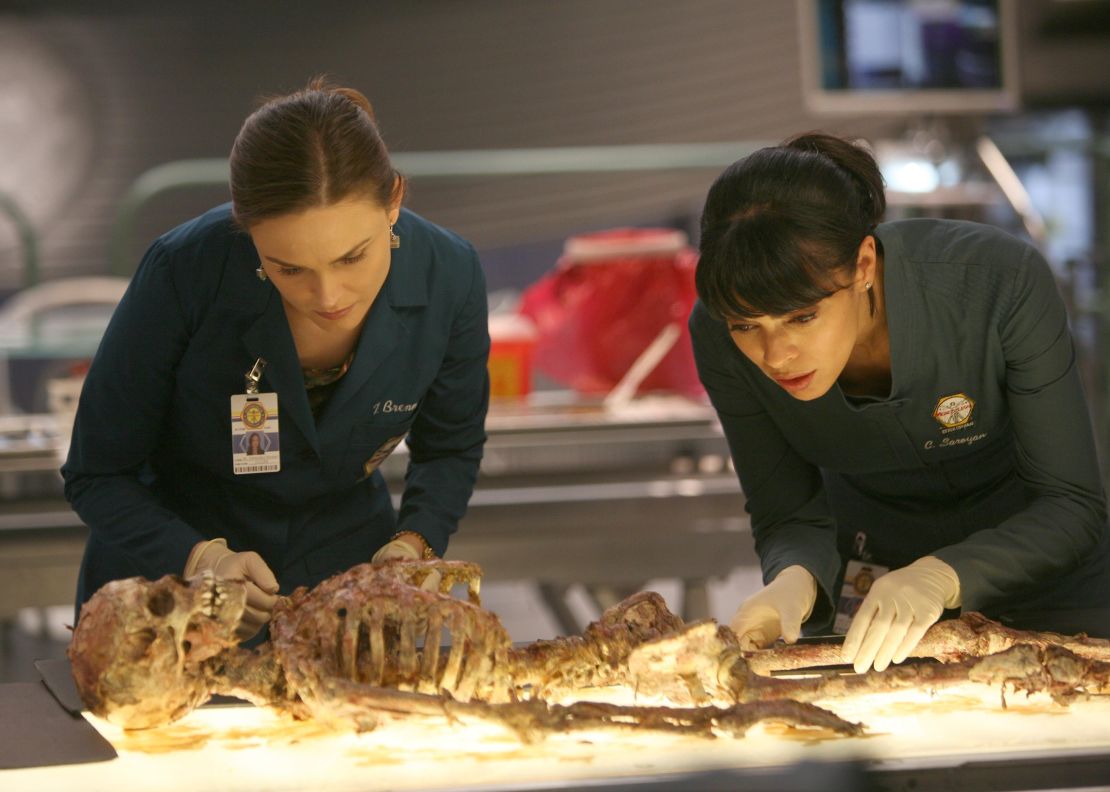 Brennan (Emily Deschanel, L) and Cam (Tamara Taylor, R) examine the remains of a young boy who could help them convict the Gravedigger in the 'Bones' episode "The Boy with the Answer."