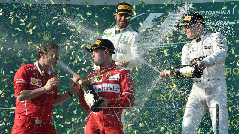 Ferrari German driver Sebastian Vettel sprays champagne at trackside engineering team member Luigi Fraboni as he celebrates his victory with runner-up Mercedes' British driver Lewis Hamilton, back left, and third-place Mercedes' Finnish driver Valtteri Bottas at the end of the Australian Grand Prix in Melbourne on Sunday, March 26. 