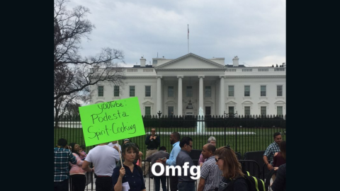 A woman stands outside the White House Sunday protesting that the "Pizzagate" conspiracy should receive more attention.