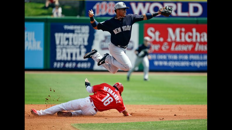New York Yankees second baseman Starlin Castro throws to first base as he leaps over Philadelphia Phillies' Cesar Hernandez in the first inning of a spring training game on Wednesday, March 22. 