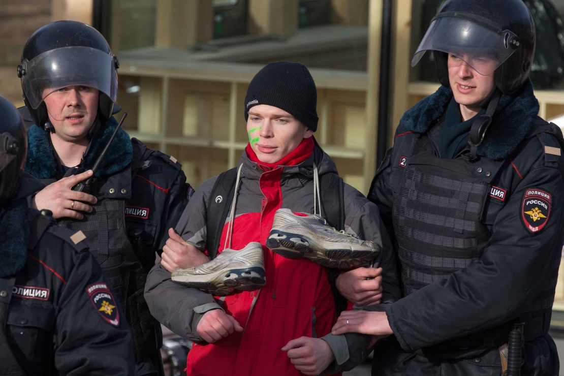 A protester, with trainers hung around his neck mocking Medvedev, is detained in Moscow on Sunday, March 26, 2017.