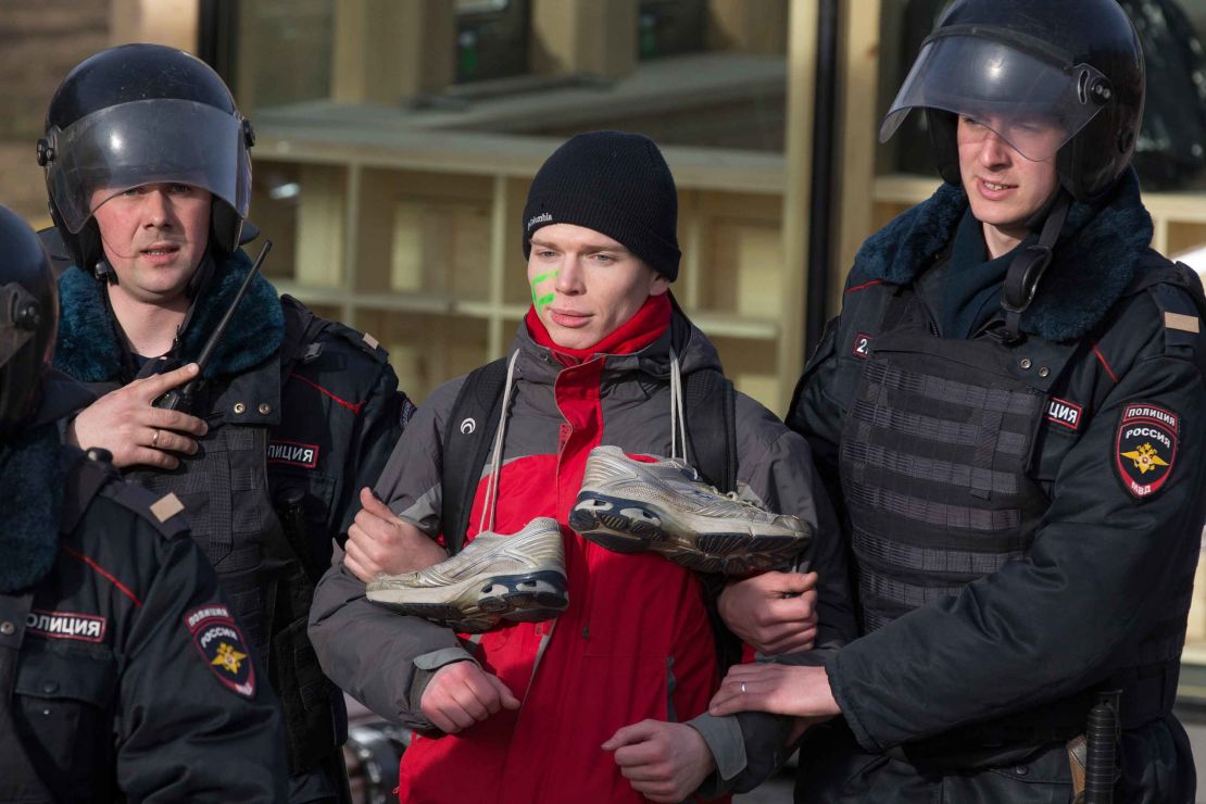 A protester, with trainers hung around his neck mocking Medvedev, is detained in Moscow on Sunday, March 26, 2017. 