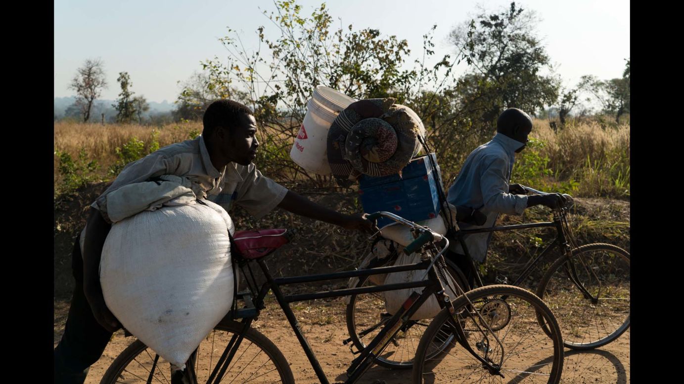 Two South Sudanese men push their bicycles after crossing the border. They've been on the road from Yet to Uganda for a month.