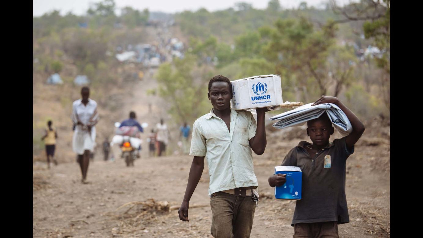 South Sudanese refugees carrying Core Relief Items walk down a road in Bidibidi refugee settlement, Yumbe District, Northern Region, Uganda.