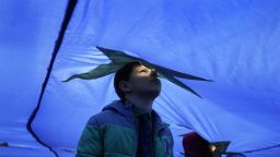 A child peers through a wind vent in a huge European Union flag during a March 25 event marking 60 years since the founding of the alliance.