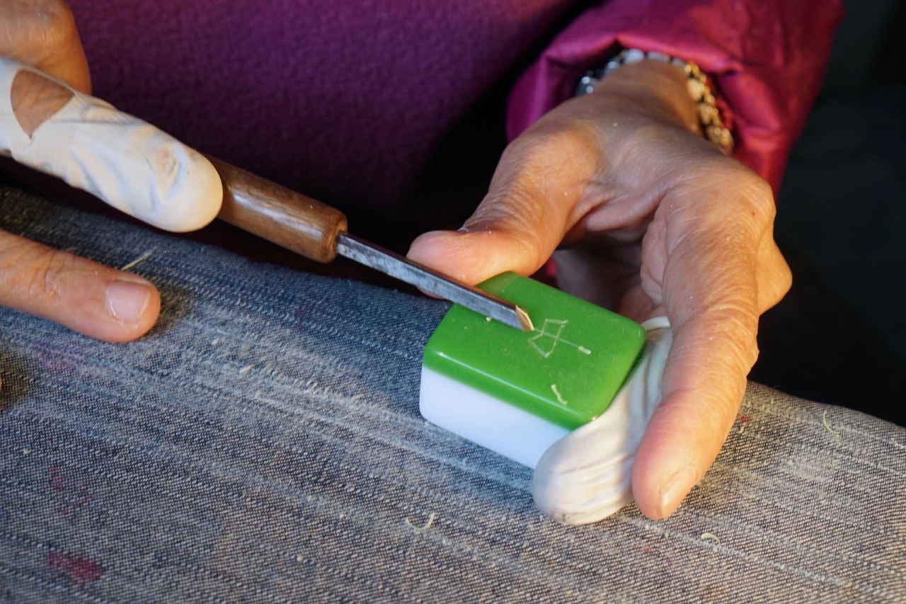 Ho softens the hard plastic using a heated lamp, before etching the patterns.