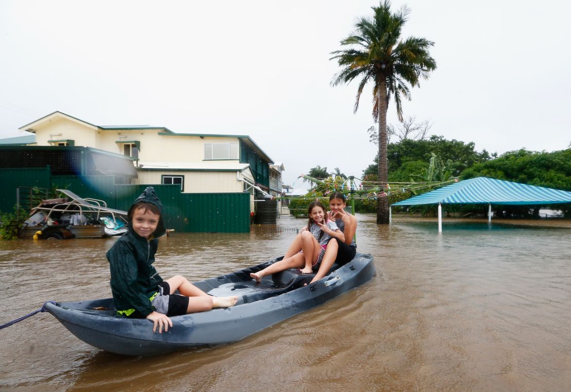 Three children paddle in a kayak  after flood waters entered their backyard on March 30, in Murwillumbah, Australia.