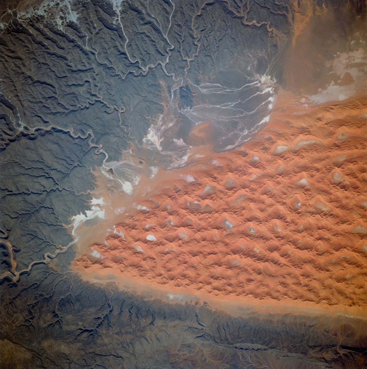 The Tifernine dunes of east-central Algeria are pictured in this image, captured in 1995. "The dunes lie in a basin of dark-colored rocks heavily cut by winding stream courses (top right)," explains the caption in the Nasa Image and Video Gallery. "Very occasional storms allow the streams to erode the dark rocks and transport the sediment to the basin. Winds then mold the stream sediments into the complex dune shapes so well displayed here."