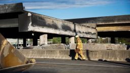 A firefighter walks past a section of an overpass that collapsed from a large fire on Interstate 85 in Atlanta, Friday, March 31, 2017. Many commuters in some of Atlanta's densely populated northern suburbs will have to find alternate routes or ride public transit for the foreseeable future after a massive fire caused a bridge on Interstate 85 to collapse Thursday, completely shutting down the heavily traveled highway. (AP Photo/David Goldman)