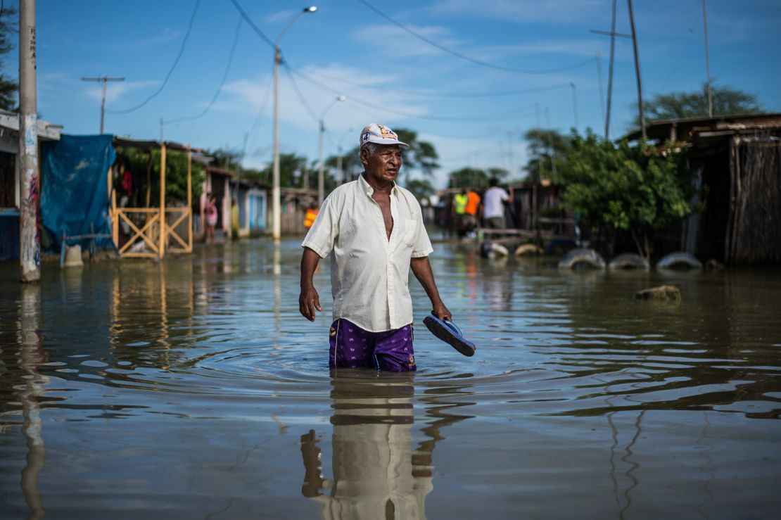 A local resident wades through water on a street in the "El Indio" settlement on the outskirts of Piura, in northern Peru.